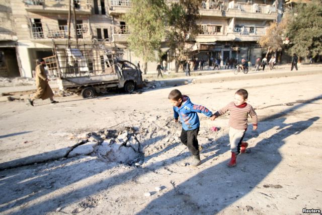 Boys run near a hole in the ground after airstrikes by pro-Syrian government forces in the rebel-held al-Sakhour neighborhood of Aleppo, Syria, Feb. 8, 2016.