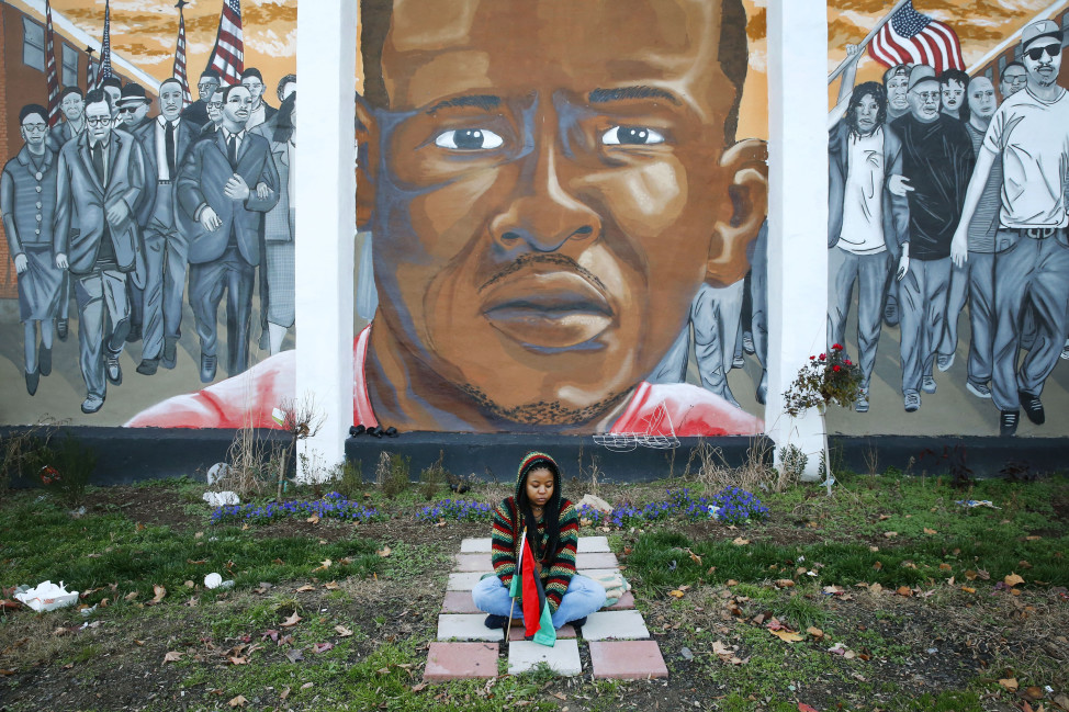 Jazmin Holloway sits below a mural depicting Freddie Gray at the intersection of his arrest on Dec. 16, 2015 in Baltimore. (AP)