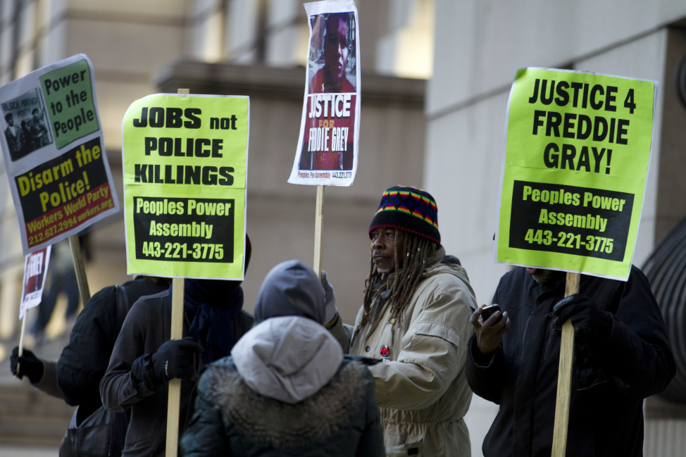 Demonstrators hold up signs outside the courthouse of a trial in connection with the death of Freddie Gray on Jan. 11, 2016, in Baltimore. (AP)