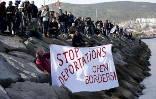 Activists hold a banner as migrants arrive in the Turkish coastal town of Dikili on the first day of an EU brokered deal to deport migrants in Greece on April 4, 2016. (Reuters)