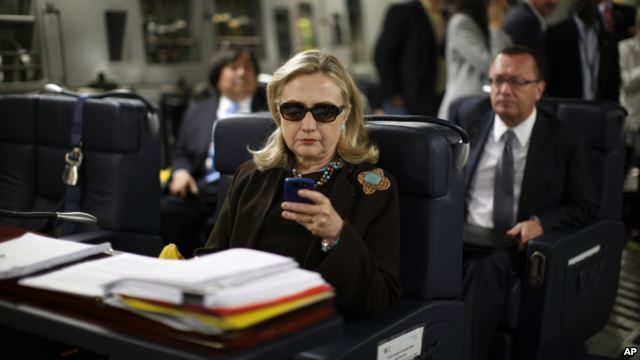 FILE - Then-secretary of state Hillary Clinton checks her BlackBerry from a desk inside a C-17 military plane upon her departure from Malta, in the Mediterranean Sea, bound for Tripoli, Libya, Oct. 18, 2011. 