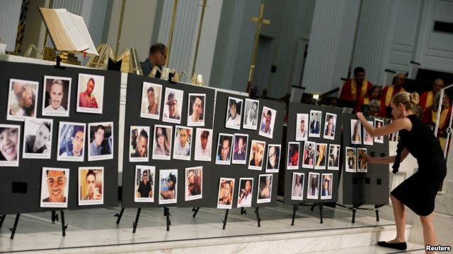 A woman places a photograph of one of the victims in the shooting at the Pulse gay nightclub, on a memorial during an Interfaith Service at First United Methodist Church in Orlando, Florida, June 14, 2016.