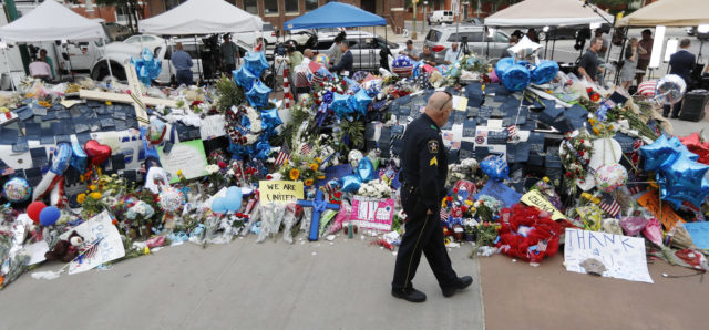 A policeman visits a makeshift memorial at the Dallas police headquarters, Monday, July 11, 2016, in Dallas. Five police officers were killed and several injured during a shooting in downtown Dallas July 7. (AP) 