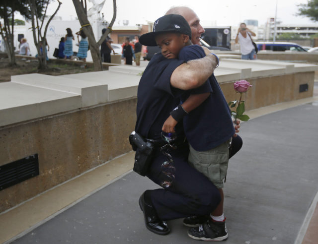  A Dallas Police officer hugs a child who came to pay respects at a makeshift memorial at Dallas Police Headquarters following the multiple police shootings in Dallas, Texas, U.S., July 9, 2016. (Reuters) 