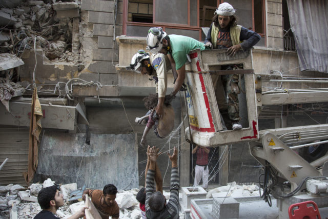 Syrian rescuers hand the body of a girl down to civilians on the ground after she was pulled from rubble of a budling following government forces air strikes in the rebel held neighborhood of Al-Shaar in Aleppo on September 27, 2016. Syria's army took control of a rebel-held district in central Aleppo, after days of heavy air strikes that have killed dozens and sparked allegations of war crimes. (AFP) 