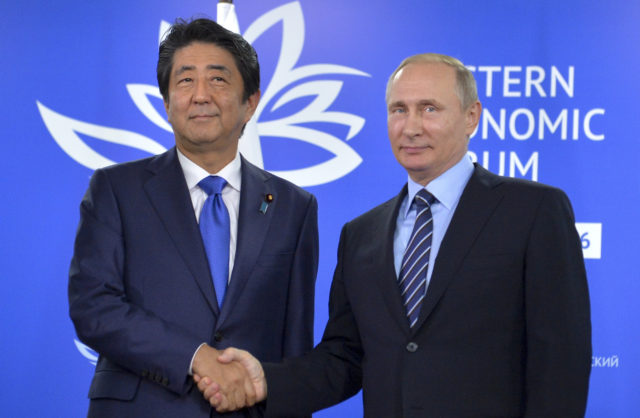 Russian President Vladimir Putin, right, and Japanese Prime Minister Shinzo Abe shake hands as they pose for a photo during their meeting in Vladivostok, Russia, Sept. 2, 2016. (AP)