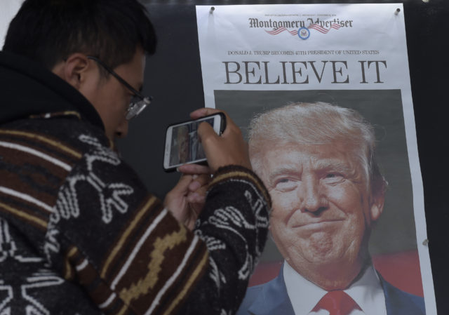 Zheng Gao of Shanghi, China, photographs the front pages of newspapers on display outside the Newseum in Washington, Nov., 9, 2016, the day after Donald Trump won the presidency. (AP)