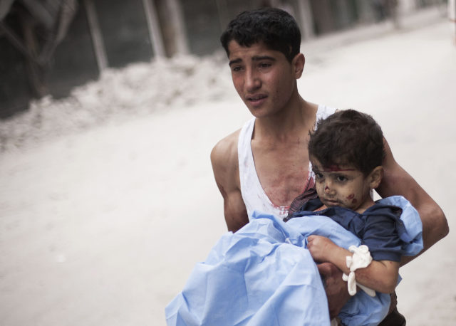 A Syrian young man holds a child wounded by Syrian Army shelling near Dar El Shifa hospital in Aleppo, Syria, Thursday, Oct. 11, 2012. (AP) 