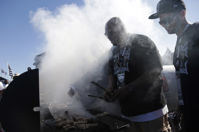 Oakland Raiders fans grill while tailgating in the stadium parking lot before an NFL football game between the Raiders and the San Diego Chargers in Oakland, Calif., Oct. 12, 2014. (AP Photo)
