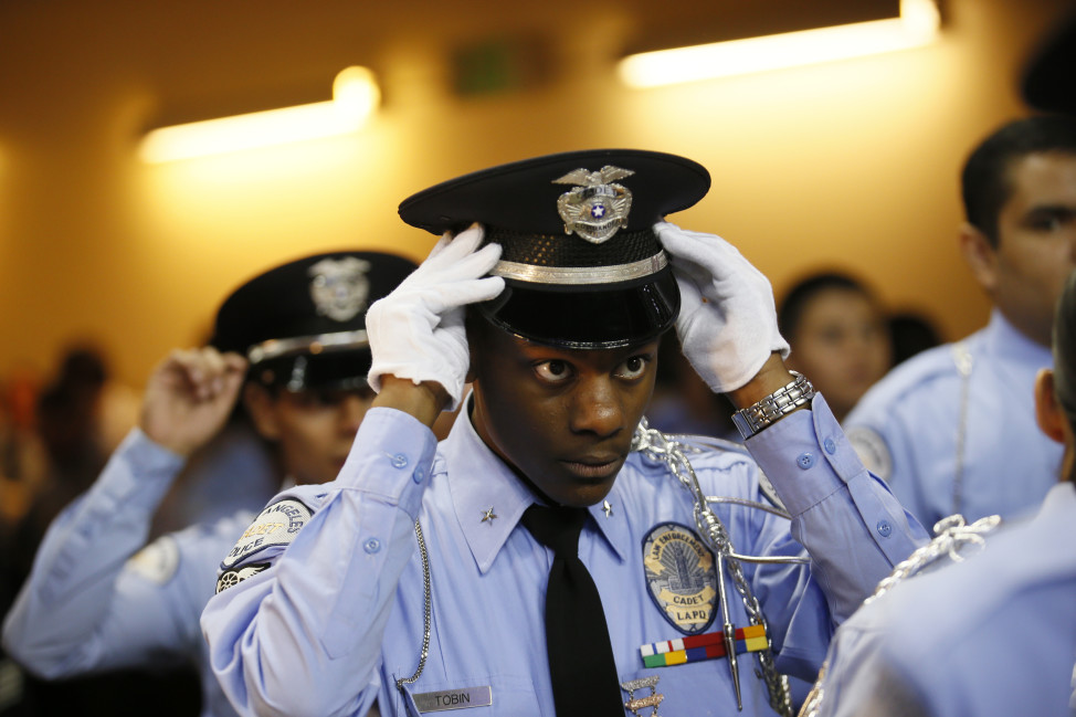 An LAPD cadet commander adjusts his hat before the LAPD cadet program graduation on Nov. 22, 2014, in Los Angeles. Police officers in the United States earn an average annual salary of $58,720. (AP Photo) 