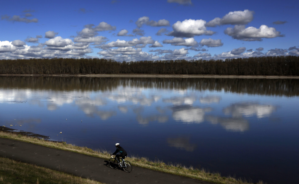 A bicyclist glides past the Columbia River in Portland, Oregon. (AP Photo)