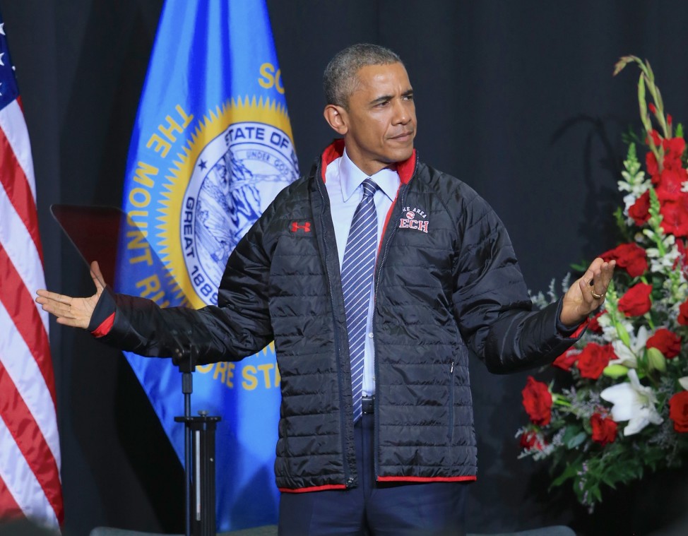 President Barack Obama puts on a gift jacket presented to him by graduates of the Lake Area Technical Institute, after delivering the commencement address to the 2015 graduating class of Lake Area Technical Institute, in Watertown, South Dakota, May 8, 2015. (AP Photo)