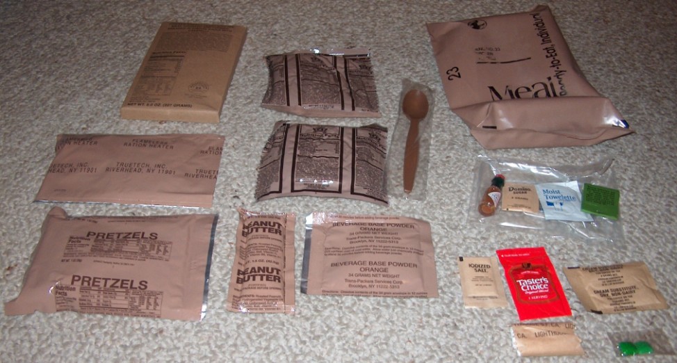 Contents of a United States Army Meal, Ready-to-Eat (from left to right): Chicken breast, pineapple pound cake, outer packaging, MRE Heater (to heat the main meal), wheat snack bread, spoon, Tabasco sauce, sugar, moist towelette, matches, pretzels, peanut butter, orange beverage base powder, salt, tea, coffee cream, toilet paper, chewing gum (Laxative) (Photo via Wikimedia Commons)