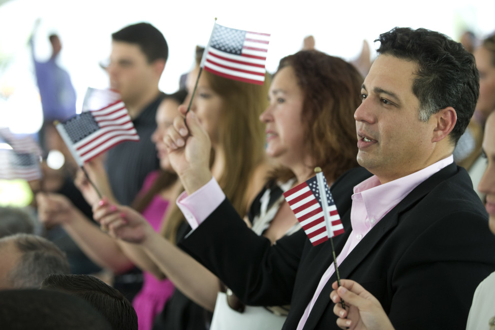 New citizens wave American flags during a U.S. Citizenship and Immigration Services naturalization ceremony on the campus of Florida International University, July 6, 2015, in Miami, Florida. (AP Photo)