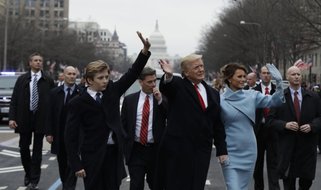 President Donald Trump waves as he walks with first lady Melania Trump and their son Barron during the inauguration parade on Pennsylvania Avenue in Washington, Friday, Jan. 20, 2016. (AP Photo/Evan Vucci, Pool)
