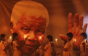 Schoolgirls hold candles in front of poster of former South African President Mandela during prayer ceremony at school in Chennai