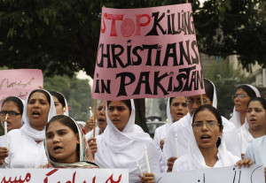 Members of Pakistani Christian community hold placard as they shout slogans during protest rally to condemn Sunday's suicide attack in Peshawar on a church, with others in Lahore