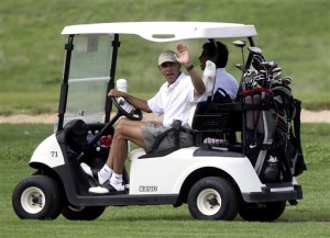 Presiden Obama melambaikan tangan dari atas kereta golf.