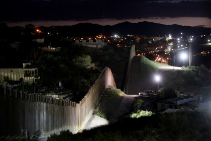 The US/Mexico border wall is illuminated at night July 6, 2012 in Nogales, Arizona.