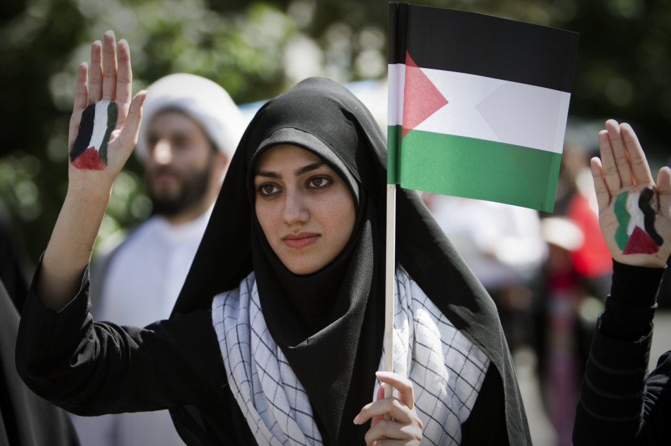 An Iranian woman holds a Palestinian flag as she shows her palm painted in the colors of the Palestinian flag during the 'Quds Day' rally, an anti-Israeli demonstration in solidarity with Palestinians in Tehran. (AFP)