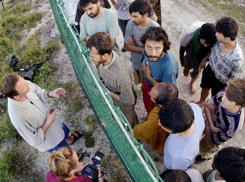 Refugees gather on one side of a fence to talk with international journalists about their journey that brought them to the Island of Nauru, Wednesday, Sept. 19, 2001. The refugees were part of 517 rescued from sinking boats north of Australia and will be detained until their claims for asylum can be processed. (AP Photo/Rick Rycroft)