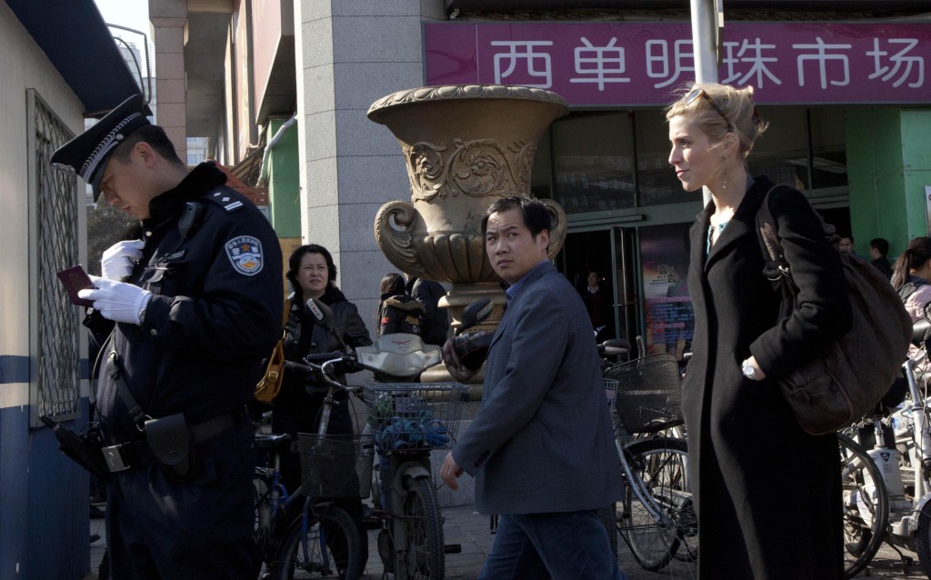 A Chinese police man checks the identity of a foreign journalist near the Xidan shopping district, one of two sites designated on an internet call for protest in Beijing, China, Sunday, March 6, 2011. The Chinese capital began ramping up controls on foreign journalists amid calls on the Internet for anti-government protests styled on those rocking the Middle East and North Africa. 