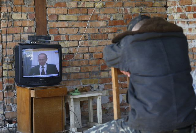 A Ukrainian serviceman watches a TV broadcast of Russian President Vladimir Putin signing a law on ratification of a treaty making Crimea part of Russia, at a Ukrainian military base in the Crimean town of Belbek March 21, 2014. Russia's upper house of parliament unanimously approved a treaty on annexing Ukraine's Crimea region on Friday, clearing the way for President Vladimir Putin to sign it into law. REUTERS/Vasily Fedosenko 