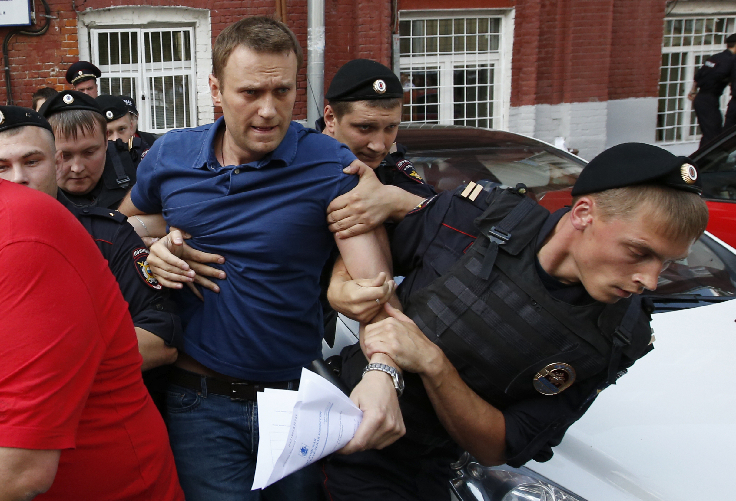 Policemen detain Russian opposition leader and anti-corruption blogger Alexei Navalny (C), after he visited the city's election commission office to submit documents to get registered as a mayoral election candidate, in Moscow July 10, 2013. Protest leader Alexei Navalny vowed he would destroy the political system under President Vladimir Putin that was "sucking the blood out of Russia", after state prosecutors demanded he be jailed for six years on theft charges. Other opposition figures say the trial was intended to prevent Navalny from fulfilling his dream of becoming president and, before that, running for Moscow mayor in September. Navalny was detained on a charge of organizing an unsanctioned rally near the city's election commission office and was then released in less than half an hour. REUTERS/Grigory Dukor 