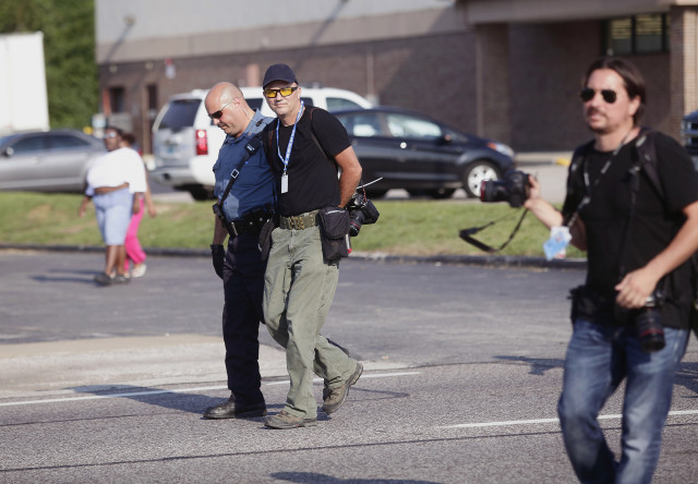 Getty Images photographer Scott Olson (C) is arrested by a highway patrol officer during a protest for the shooting death of Michael Brown, in Ferguson, Missouri August 18, 2014. He was arrested because police required media to be within certain areas, media quoted another journalist as saying. Missouri Governor Jay Nixon lifted the curfew for the St. Louis suburb of Ferguson on Monday and began deploying National Guard troops to help quell days of rioting and looting spurred by the fatal shooting of the black unarmed teenager by a white policeman.    REUTERS/Joshua Lott 
