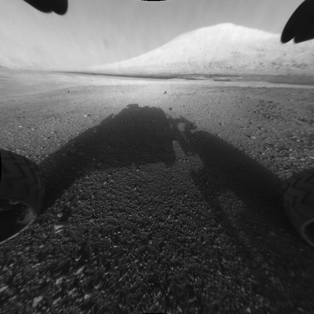 This image taken by Curiosity shows what lies ahead for the rover -- its main science target, Mount Sharp. The rover's shadow can be seen in the foreground, and the dark bands beyond are dunes. (Image: NASA/JPL-Caltech)