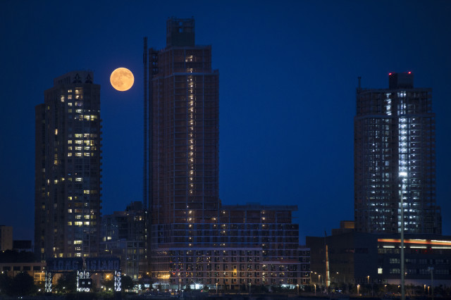 On Saturday, July 12, 2014 the world was treated to a remarkable sight in the night sky; a “supermoon”.  Also called a perigee moon, it’s shown here rising over the Queens borough of New York.  Scientists say that a “supermoon” takes place when the moon is close to the horizon, making it appear larger and much brighter than other “regular” full moons. (AP)