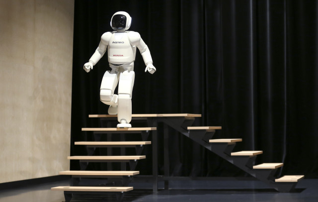 Taking a leisurely stroll down a set of stairs is the latest version of Honda's Asimo humanoid robot.  With enhanced intelligence and more nimble hand dexterity, the new robot was introduced to the public at an exhibition held near Brussels on July 16, 2014.  (Reuters) 