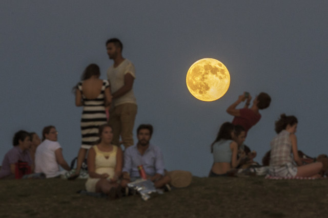 Gathering in a Madrid park, people enjoy the spectacular sight of a perigee moon, also known as a supermoon, as it rises above them on Sunday, Aug. 10, 2014. A supermoon takes place when the moon is near the horizon and appears larger and brighter than other full moons. (AP)