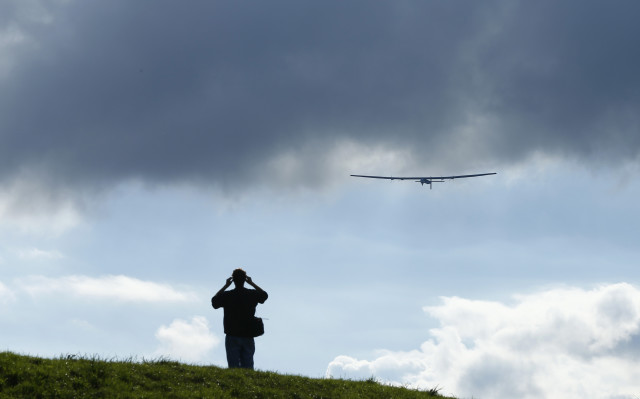 A man watches a test flight of the solar-powered Solar Impulse 2 experimental aircraft, piloted by Swiss Bertrand Piccard, in Payerne November 13, 2014.  An attempt to fly around the world in stages using only solar energy will be made in 2015. (Reuters)