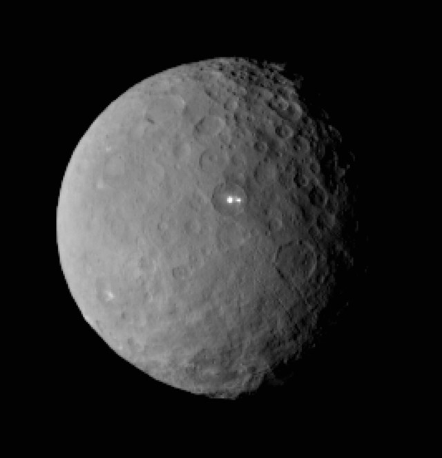 This is an image of the dwarf planet Ceres taken by NASA’s Dawn spacecraft on 2/19/15 from a distance of nearly 46,000 kilometers.  It shows that the mysterious bright spot, noticed earlier by scientists, shares its basin location with a dimmer companion.  Dawn is preparing to rendezvous with Ceres and go into orbit 3/7/15 after a three-year journey. (NASA/JPL-Caltech/UCLA/MPS/DLR/IDA)