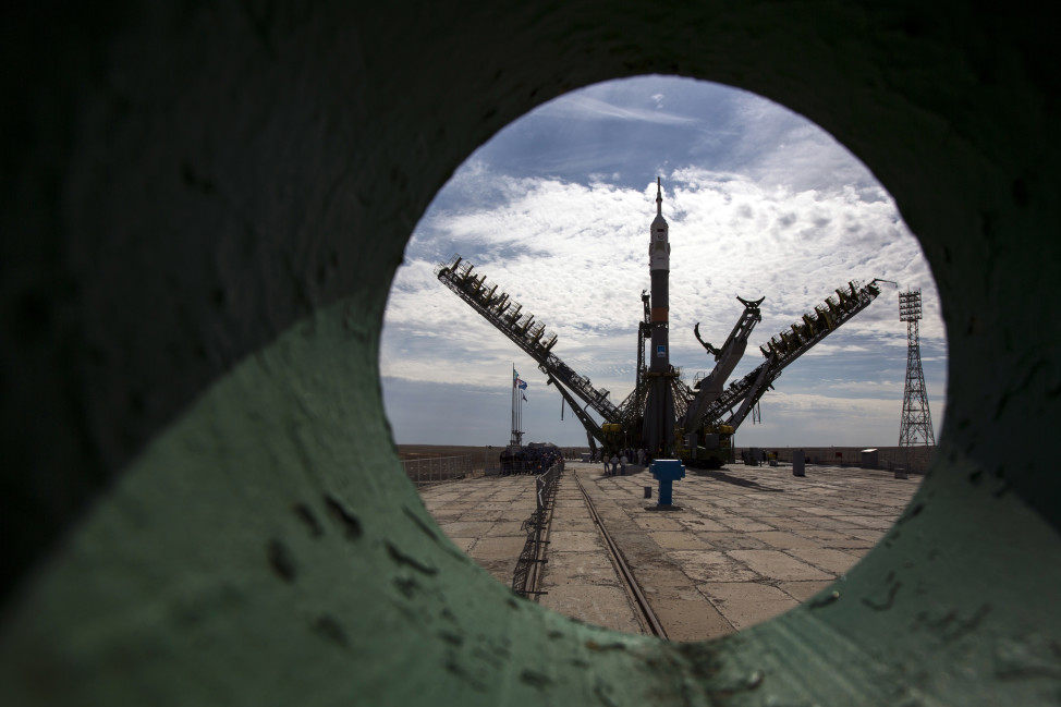 This photo, taken 7/20/15 through a pipe at the Baikonur Cosmodrome, shows a Soyuz-FG booster rocket with the space capsule Soyuz TMA-17M after being lifted onto its launch pad by three service towers.  The spacecraft, launched on 7/22/15 carried a new crew to the International Space Station. (AP) 