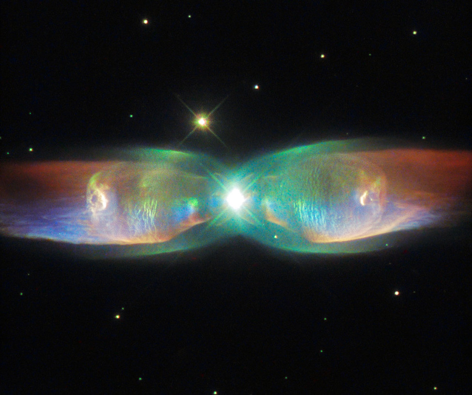 The shimmering colors visible in this NASA/ESA Hubble Space Telescope image, released 8/24/15, shows off the remarkable complexity of the PN M2-9 Twin Jet Nebula which is also known as Minkowski's Butterfly, the Wings of a Butterfly Nebula or simply Butterfly Nebula.   The luminous nebula is about 2,100 light-years away from Earth.  Unlike ordinary planetary nebulae which has one star at their center, this is a bipolar nebula which has two stars from a binary star system. (ESA/Hubble & NASA)