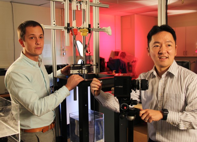 Graduate student Sean Gart (left) and Sunghwan “Sunny” Jung, an associate professor of biomedical engineering and mechanics at Virginia Tech, make adjustments in front of a machine they used to simulate the mechanics of how dogs drink water. (John Pastor/Virginia Tech)