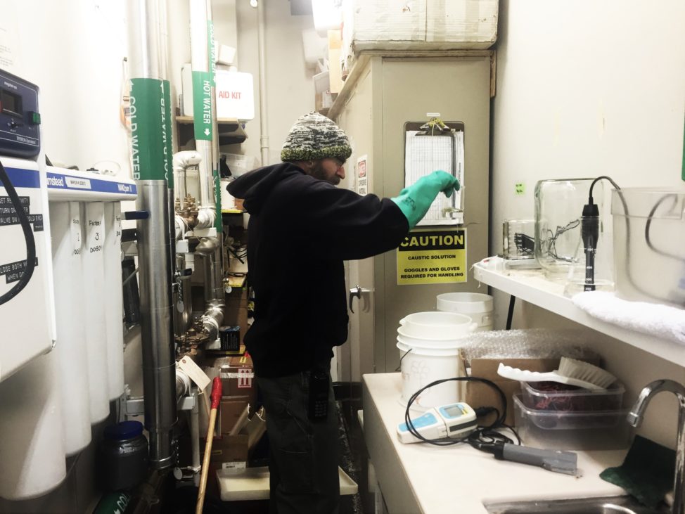 Tim Ager, a greenhouse volunteer, spends a late evening mixing nutrients for the hydroponics system. (Refael W. Klein)