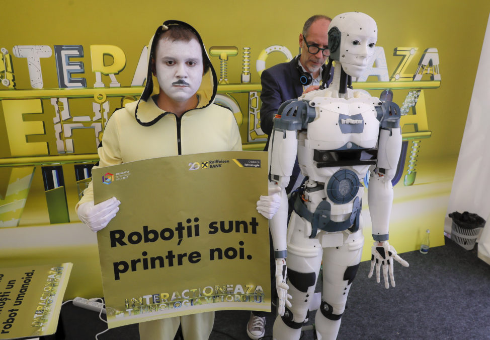 French designer Gael Langevin stands behind the InMoov robot after he unveiled it May 26 at a technology fair in Bucharest, Romania. Langevin says the robot can be programmed to speak English, Spanish, French, Russian and Dutch, with a basic model costing about 1,500 euros. An entertainer seen standing on the left of the robot holds a sign that reads "The robots are among us". (AP) 