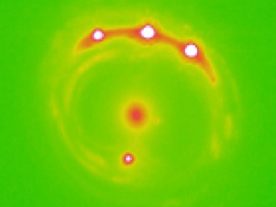 Image of the gravitational lens RX J1131-1231 galaxy with the lens galaxy at the center and four lensed background quasars. University of Oklahoma research estimate that there are trillions of planets in the center elliptical galaxy in this image. (University of Oklahoma)