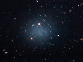 This is a galaxy that's been catalogued as NGC 1052-DF2. Astronomers call it the "see-through" galaxy since you can see right through it and observe other and more distant galaxies behind it. Researchers have found that the galaxy is missing most, if not all, of its dark matter. (NASA, ESA, and P. van Dokkum (Yale University))