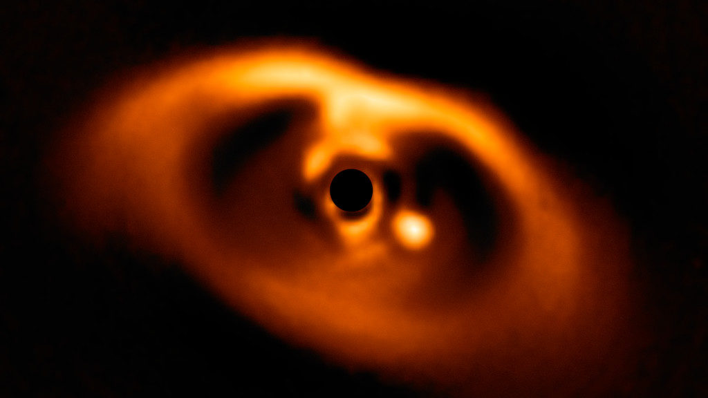 This image from the SPHERE instrument on ESO's Very Large Telescope is the first clear image of a planet caught in the very act of formation around the dwarf star PDS 70. The planet stands clearly out, visible as a bright point to the right of the centre of the image, which is blacked out by the coronagraph mask used to block the blinding light of the central star. (ESO/A. Müller et al.)