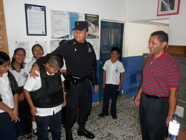 A a police officer from EL Salvador (in uniform) and the Chief of Police of Santa Ana, CA, take part in an exchange visit as part of a USAID-funded Project to familiarize kids with police work and establish a rapport. (ICMA)