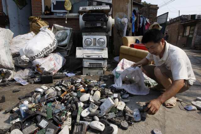 FILE - A man sorts through computer parts and phone chargers at a recycling village in Beijing. (AP)