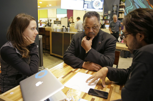 Civil rights activist, Rev. Jesse Jackson (C) visits Kacie Gonzalez (L) vice president of business development and Nick Norena, both with the company Shoto, at the Workshop Cafe in San Francisco, Dec. 8, 2014.