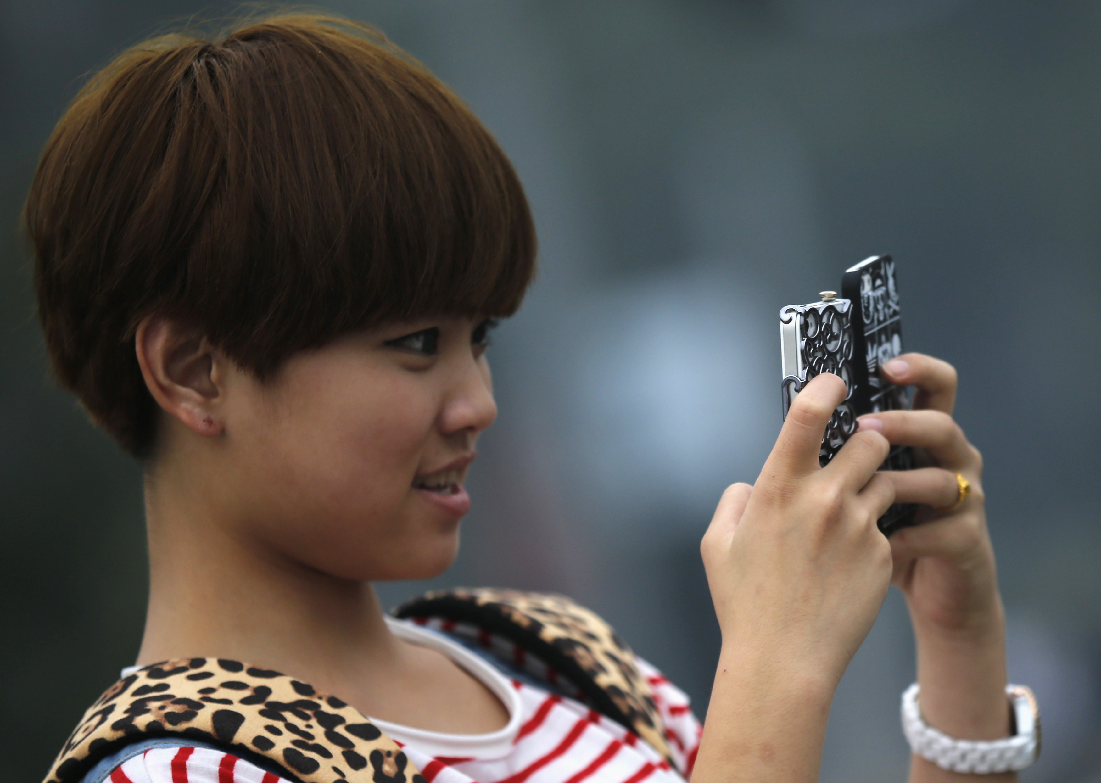 A young girl holds two mobile phones as she takes pictures at a downtown area of Shanghai, China, Oct. 22, 2012.