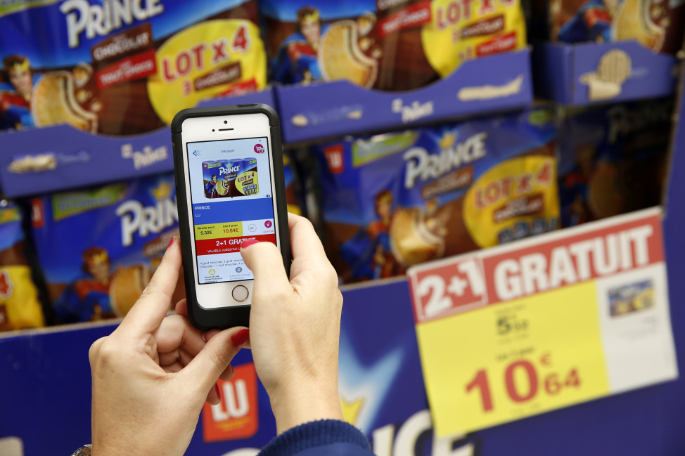 A woman demonstrates the use of the application "Promo C-Ou" on her smartphone at the Carrefour supermarket in Lille