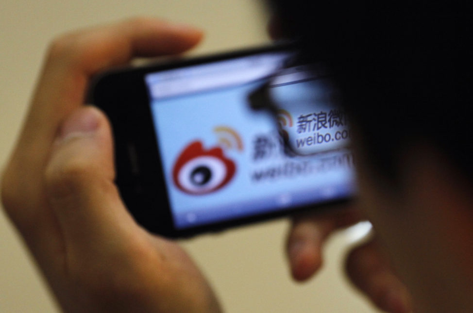 FILE - A man holds an iPhone as he visits Sina's Weibo microblogging site in Shanghai, China. (Reuters)