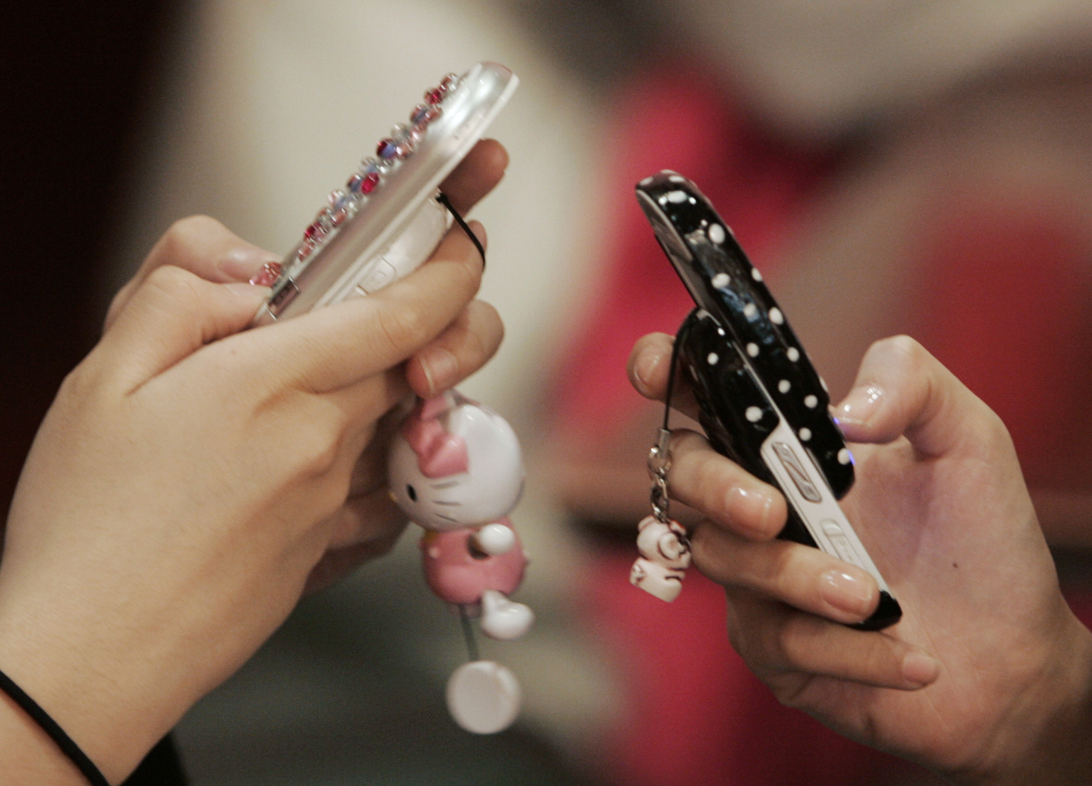 FILE - School girls use mobile phones as they chat in a restaurant in Seoul, South Korea. (Reuters)